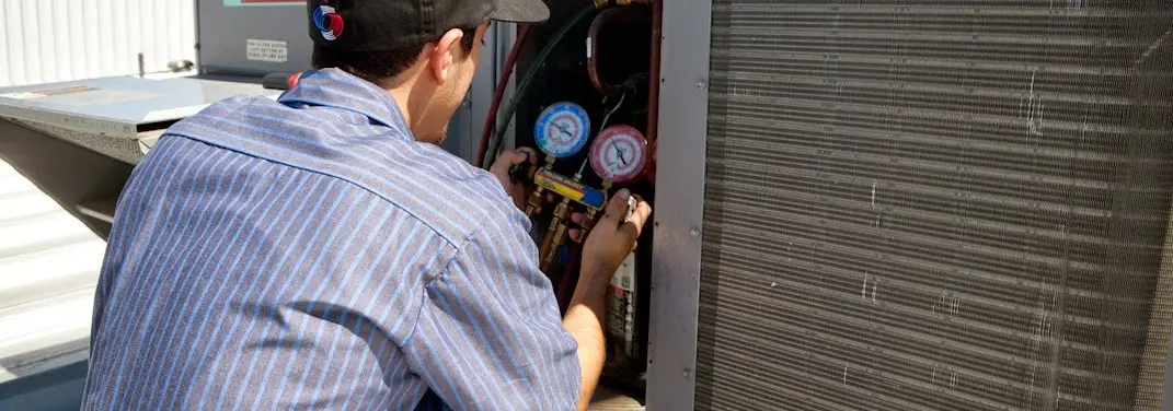 HVAC technician servicing a condenser unit in Red Oak