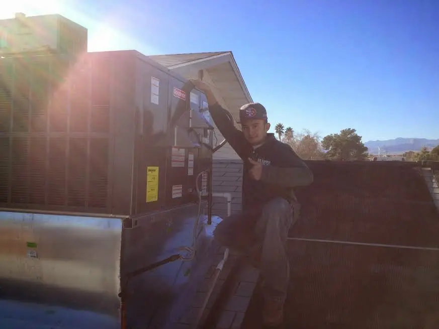 HVAC technician performing Air Duct Cleaning on a rooftop unit in Red Oak